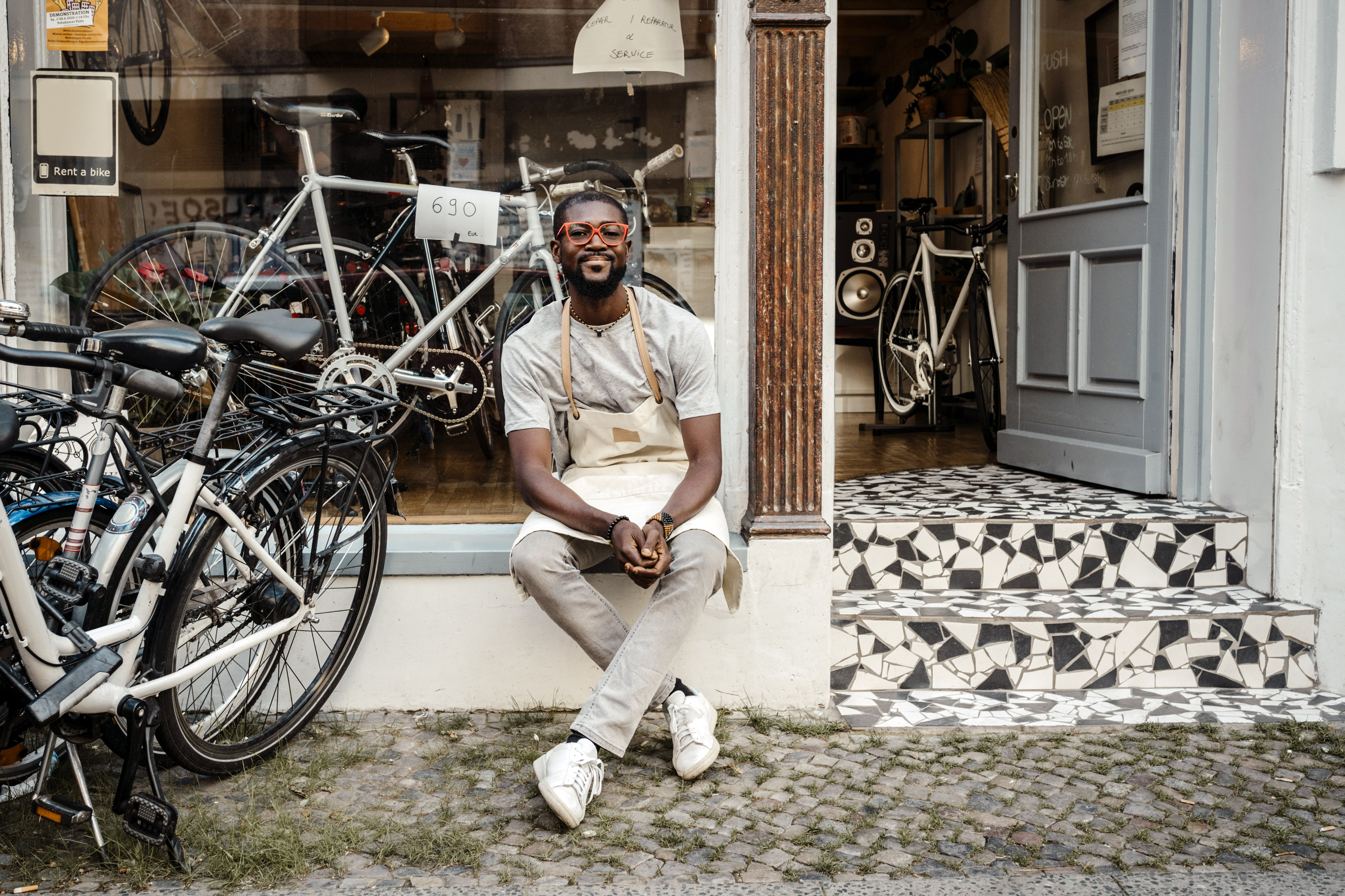 Manlig butiksägare sitter utanför sin cykelaffär